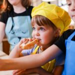 boy in blue and yellow shirt eating bread